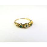 A gold ring set with two emeralds and three diamonds, shank worn, split and repair present. Size