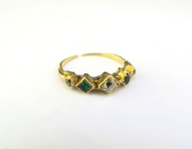 A gold ring set with two emeralds and three diamonds, shank worn, split and repair present. Size