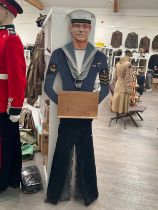 A wooden sailor cutout with display lectern