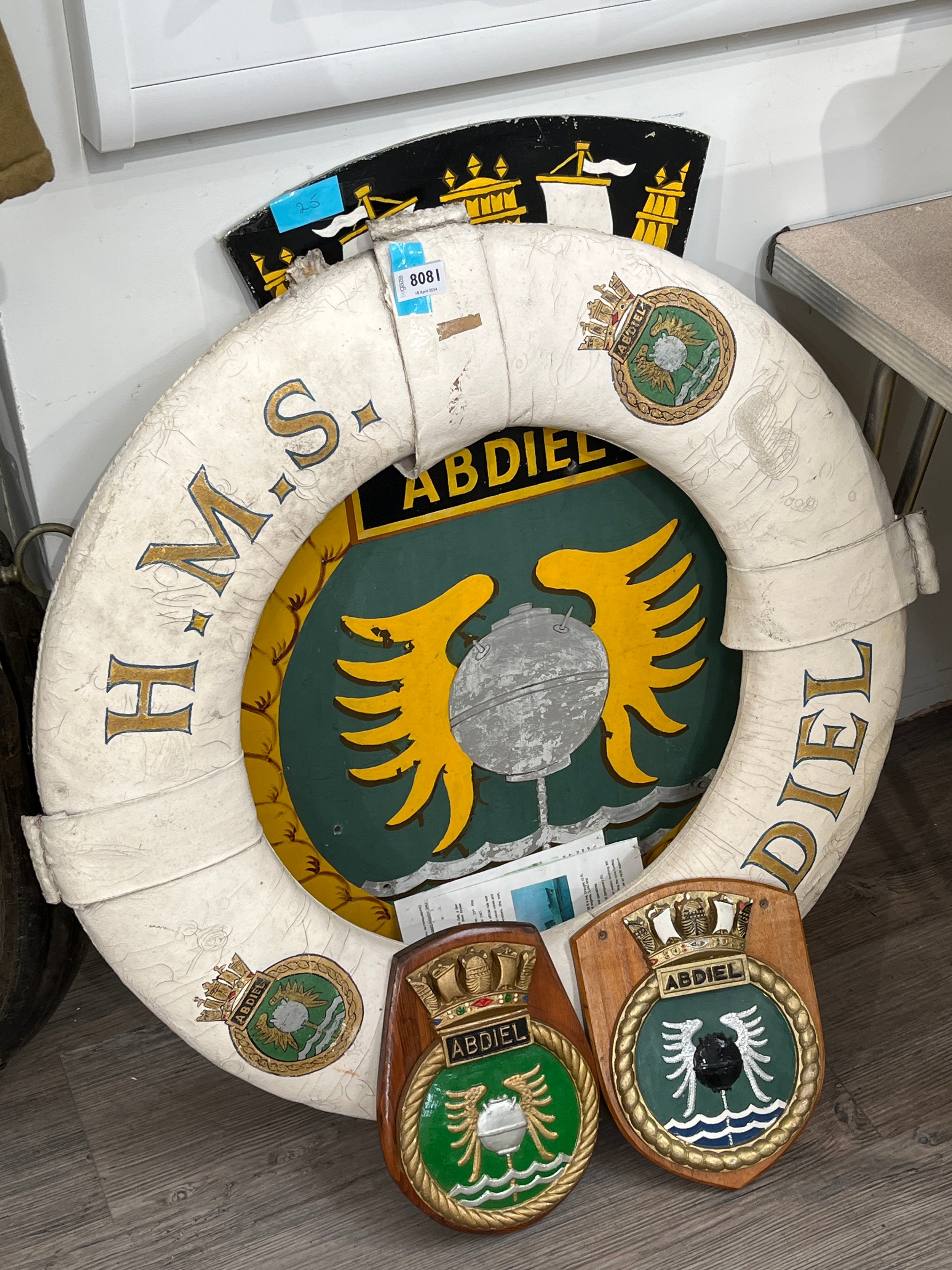 An HMS Abdiel Class lifebelt, steel crest and two wooden crests (4)