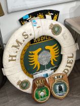 An HMS Abdiel Class lifebelt, steel crest and two wooden crests (4)