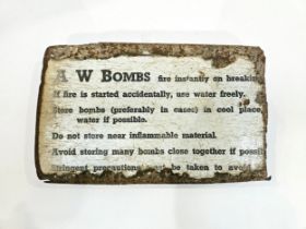 A WWII enamel sign from a case 'A W BOMBS fire instantly on breaking...' advising safe munitions