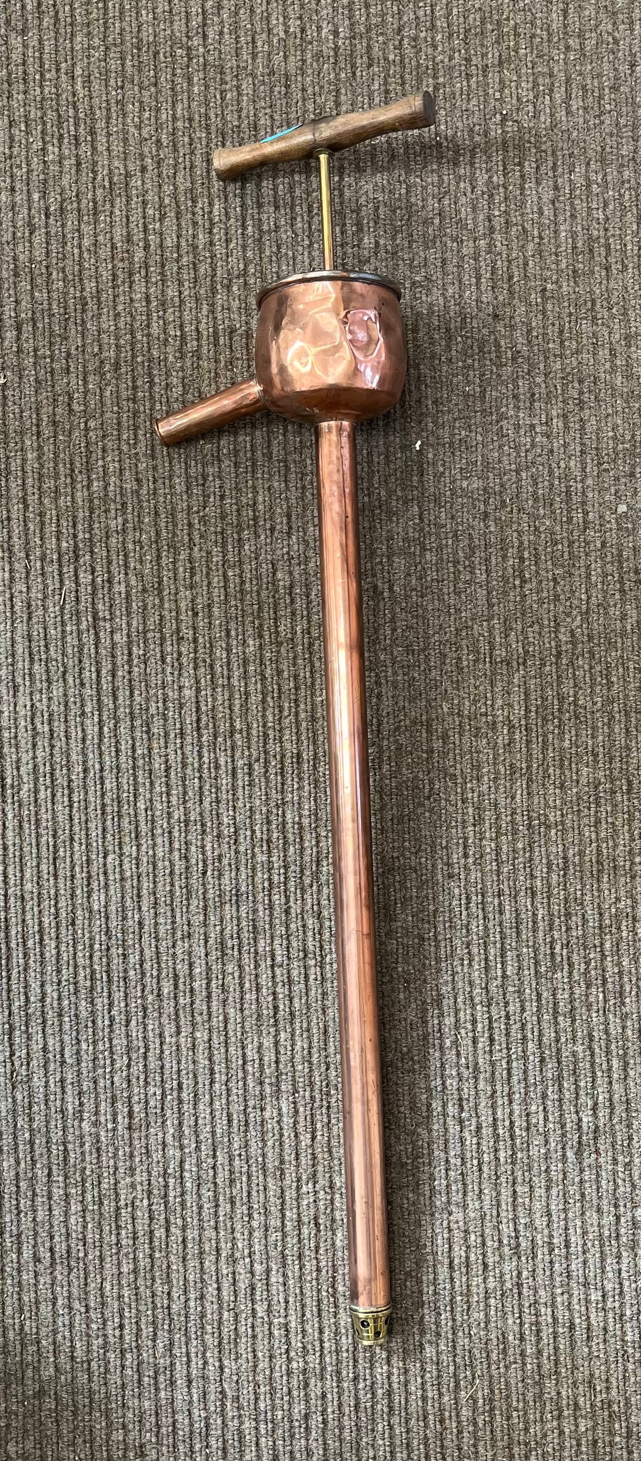 A vintage copper rum-drawing pipe