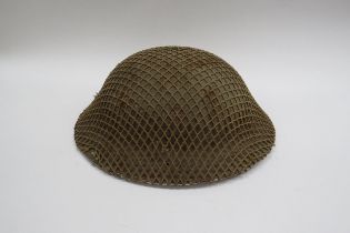 A WWII British Brodie helmet with camouflage net cover, the liner dated 1940, with chinstrap
