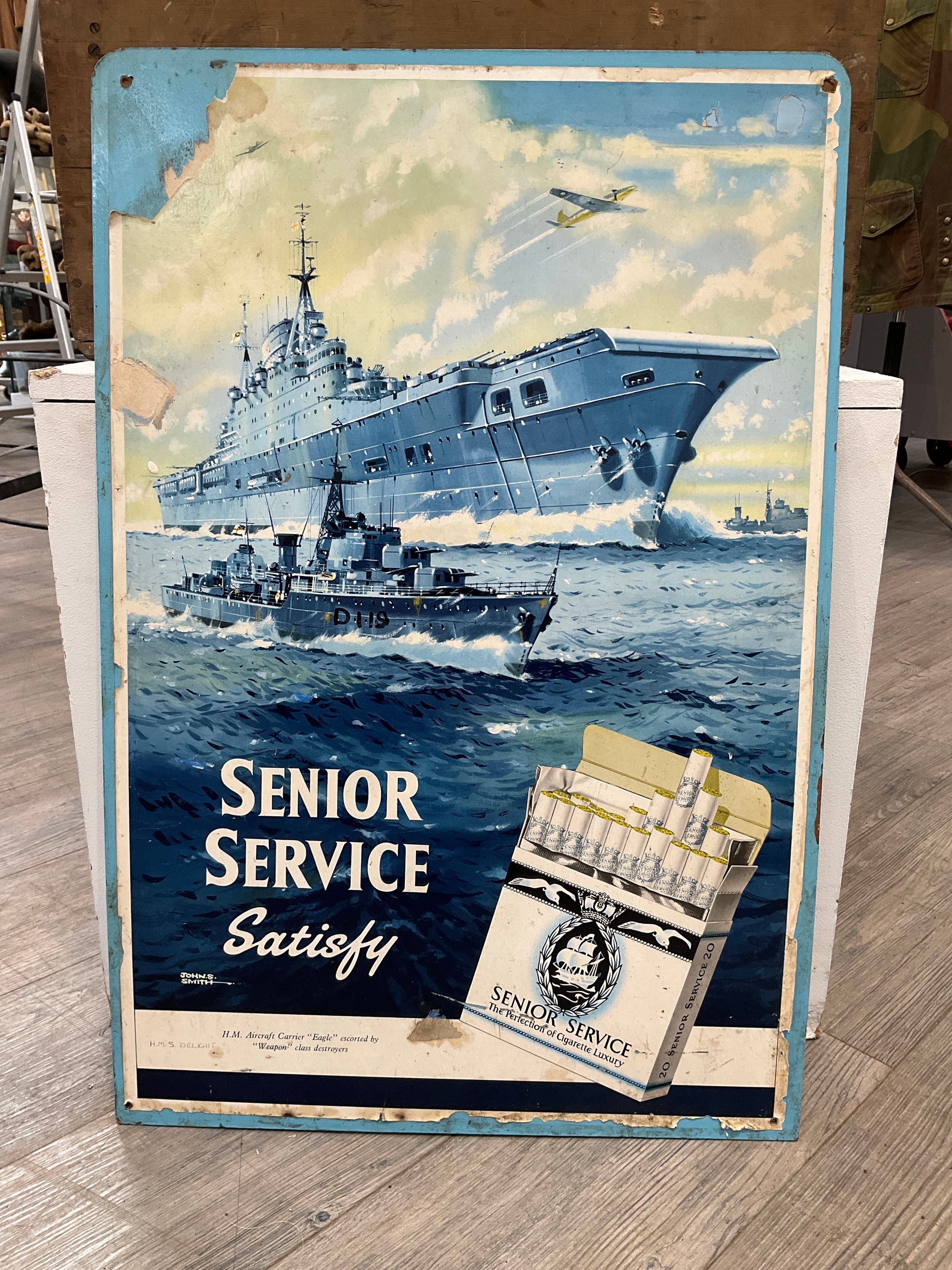 A Senior Service advertising poster by John S. Smith, design of aircraft carrier HMS Eagle, some
