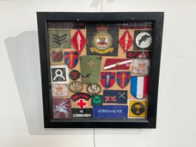 A framed display of military cloth badges including RASC, Anti Tank Gunner patch badge, 16th Air