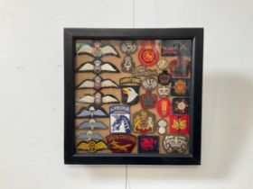 A framed display of cloth insignia including RFC, RAF and Para wings.