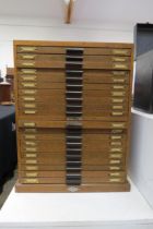 An oak 20 drawer watch makers cabinet with contents mainly 20th swiss watch parts boxed and labelled