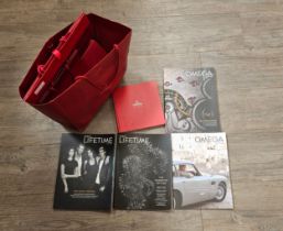 A collection of Omega bags and Omega Lifetime magazines including The No Time To Die Edition, The