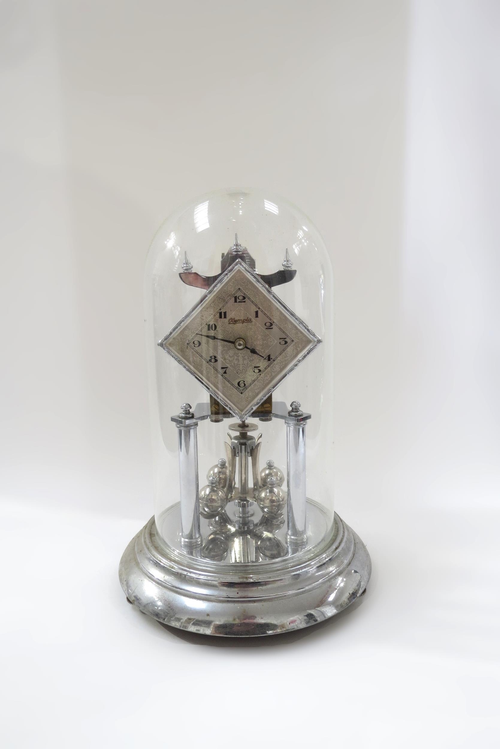 A silver coloured Olympiad anniversary clock under glass dome. 31cm tall