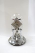 A silver coloured Olympiad anniversary clock under glass dome. 31cm tall