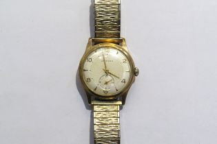 A Garrad retailed 9ct gold cased gents manual wind wristwatch. Presentation inscription to back on