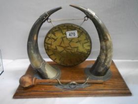 A brass dinner gong with horn supports.