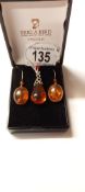 An amber pendant in silver together with amber drop earrings in silver.