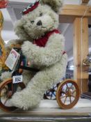 A collectors special edition cream Teddy bear on a tricycle.