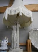 A tall plaster figural table lamp with shade.
