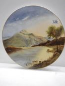 A hand painted 36 cm porcelain plaque featuring a lake and mountain scene.