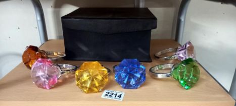 A boxed set of 6 coloured glass and white metal napkin ring holders in style of solitaire ring