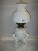 A superb quality white glazed porcelain oil lamp surmounted with cherubs and with drop in font,