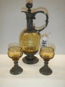 A glass and metal claret jug with two glasses.