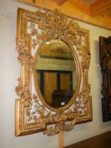 An ornate oval gilt framed mirror, frame 140 x 104 cm, mirror 78 x 59 cm, COLLECT ONLY.