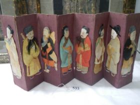 A miniature Chinese seven paneled screen with embossed fabric figures.