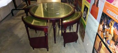 A round dark wood stained nest of tables with gilded green inserts under glass. Diameter 74cm x 48cm