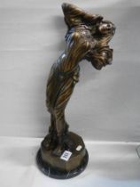A tall bronze figure of a female.
