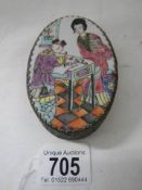 An oval pill box with enamel top.