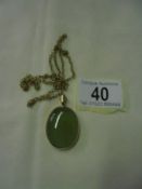 A green stone pendant in a 9ct gold mount with a yellow metal chain.