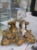 A cherub figure on a gilt stand.