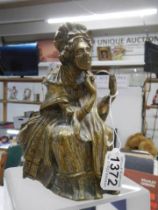 An early brass figure of an elderly lady.