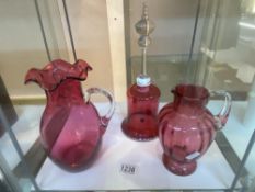2 cranberry glass jugs and a bell