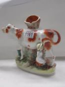 An unusual 19th century Staffordshire figure of a cow being milked.