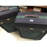 Two large matching blue suitcases on wheels with pull along handle. 1 including extra bag.