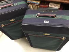 Two large matching blue suitcases on wheels with pull along handle. 1 including extra bag.