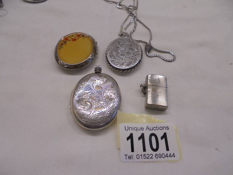 A silver locket, two white metal lockets and a miniature cigarette lighter.