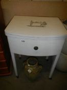 A vintage Singer sewing machine in painted cabinet/table on castors. 79H x 56W x 45 D. COLLECT ONLY.