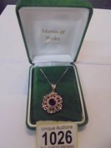 A silver pendant set with garnet stone on a silver chain,