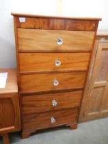An early 20th century tallboy chest of five drawers on bracket feet with glass screw in knobs,