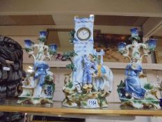 A three piece continental clock garniture comprising figural clock with candelabra side pieces.