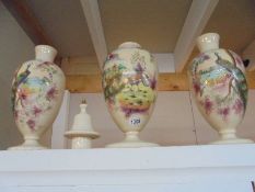A three piece 19th century hand painted garniture comprising lidded vase and pair of vases