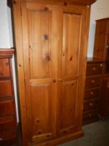 A two door pine wardrobe, top and bottom plinths removable, one knob missing, 191 cm H x 99 cm W