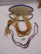 A six strand yellow stone necklace and a two strand red bead necklace.