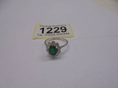 18ct white gold ring set with an oval emerald surrounded by RBC diamonds in a scalloped mount