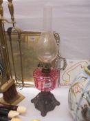 A mid-20th century oil lamp on cast metal base with cranberry glass font, COLLECT ONLY.