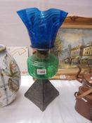 An early 20th century oil lamp on cast iron base with green glass font and blue glass shade.