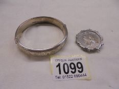 A silver bangle and a silver Victorian coin brooch.