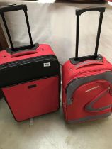 Two small red suitcase with pull along handles.