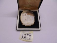 A large 19th century cameo depicting a woman feeding a young goat in a yellow metal mount.